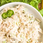 Top down view of bowl of chicken salad on wooden board.