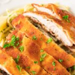 Sliced chicken schnitzel over pasta.