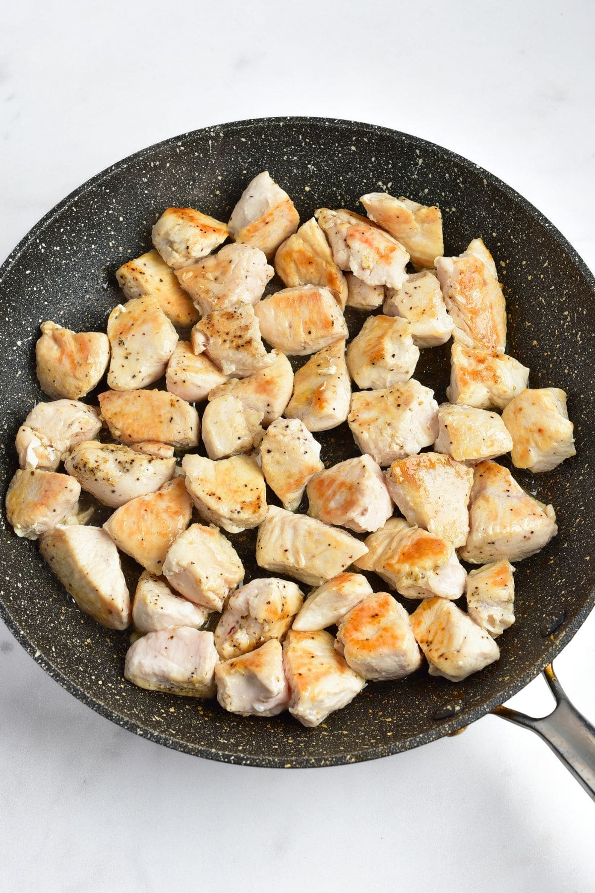 Sautéing cubed chicken breast in skillet.