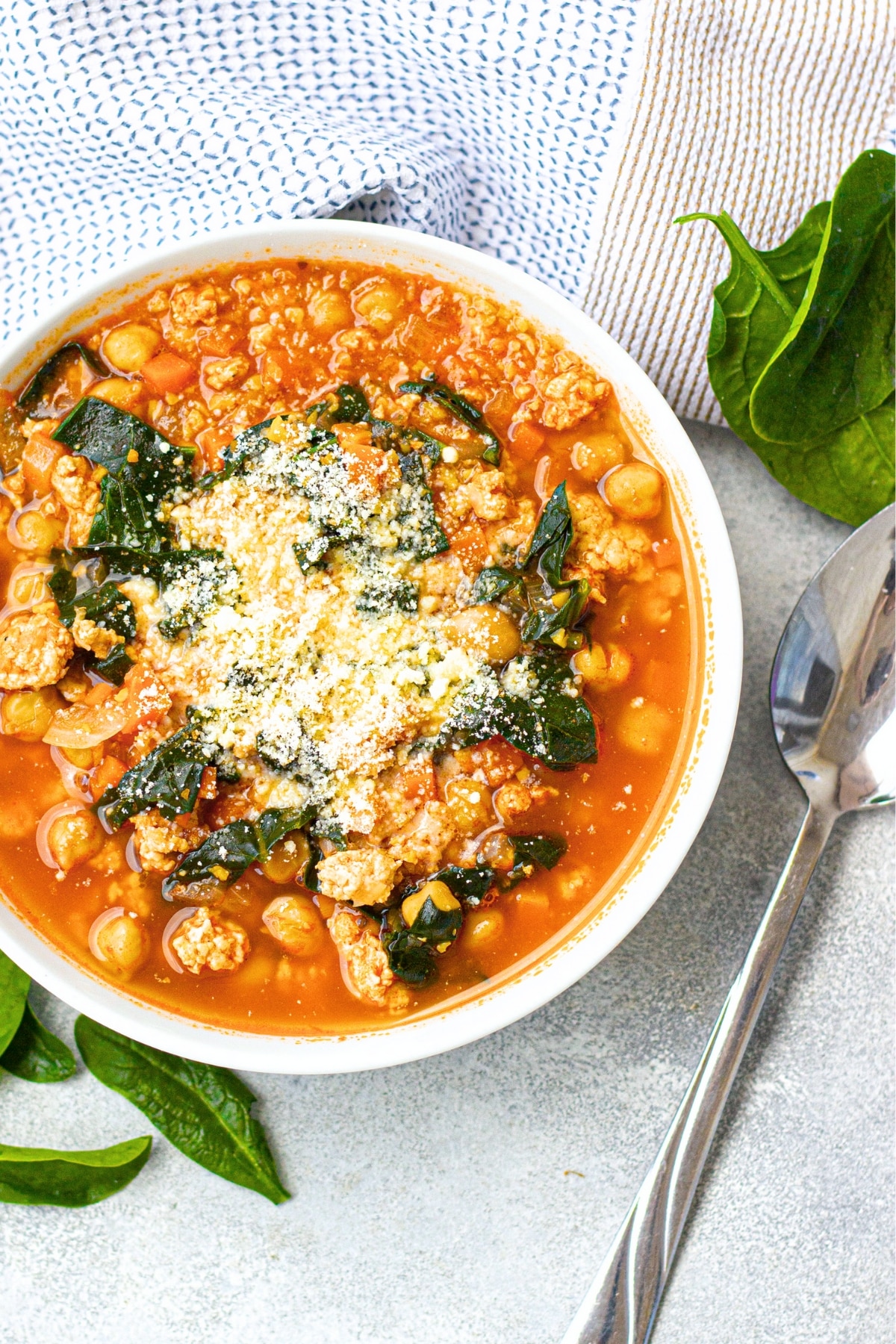 Top down view of a bowl of kale and chickpea soup on board.