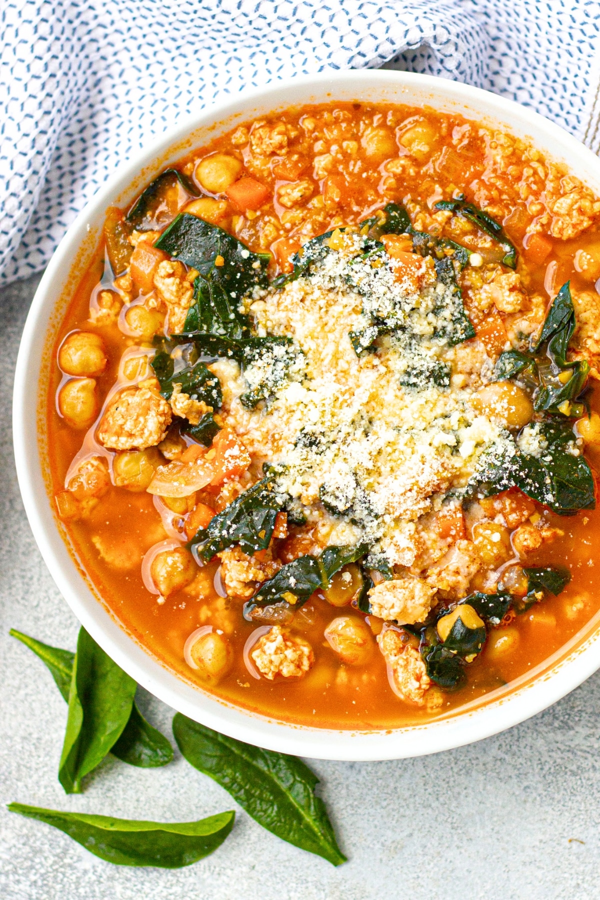Top down view of a bowl of chickpea kale soup sprinkled with parmesan cheese.