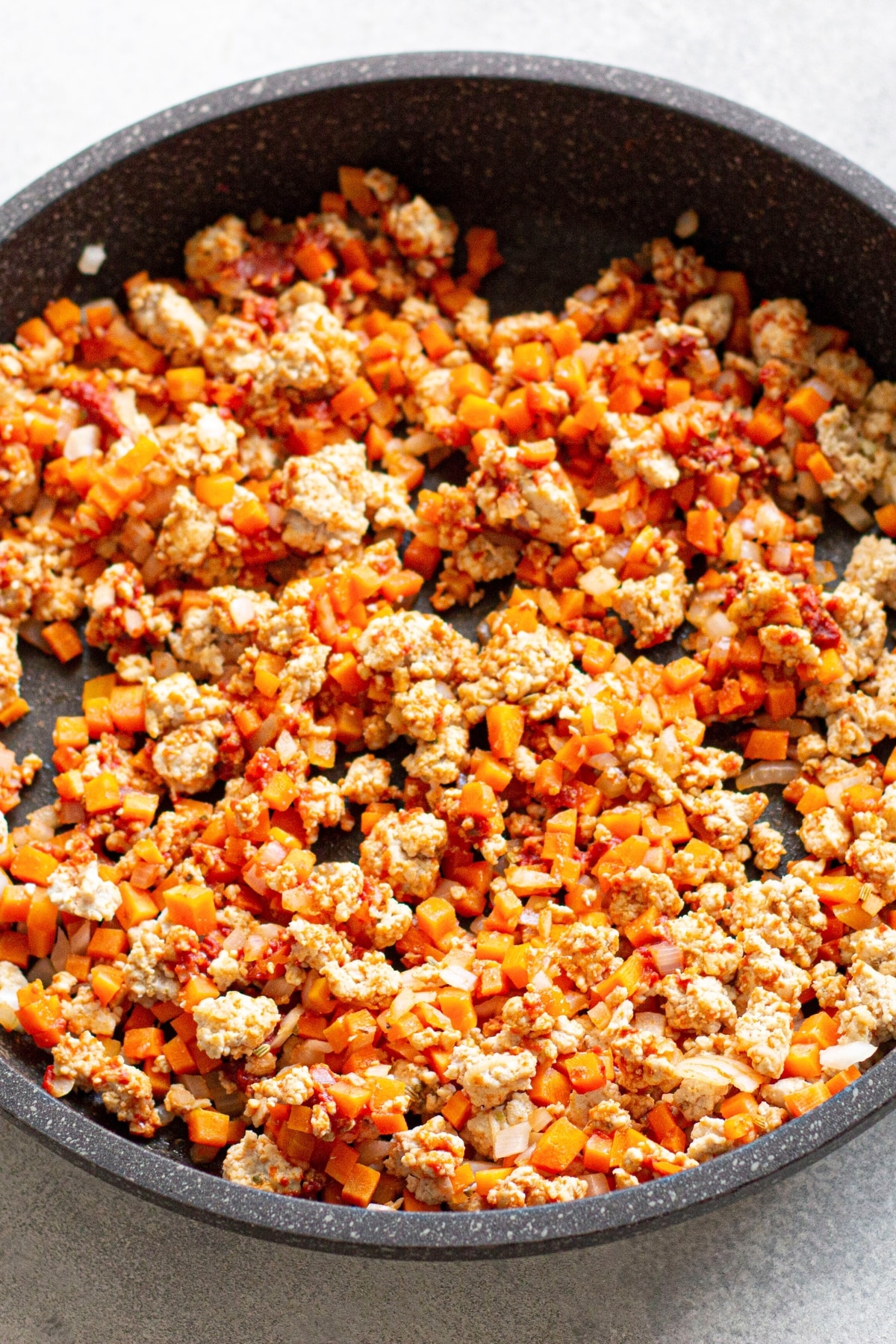 Cooking chicken, carrots and onions in skillet.