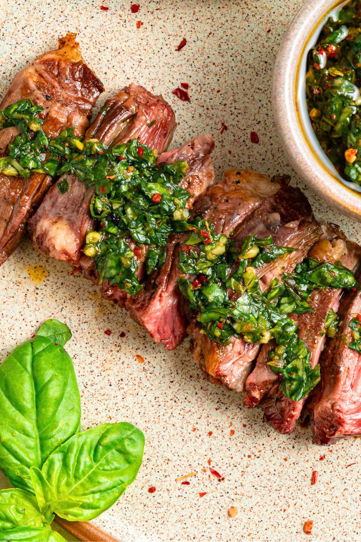 Top down view of basil chimichurri sauce over sliced steak