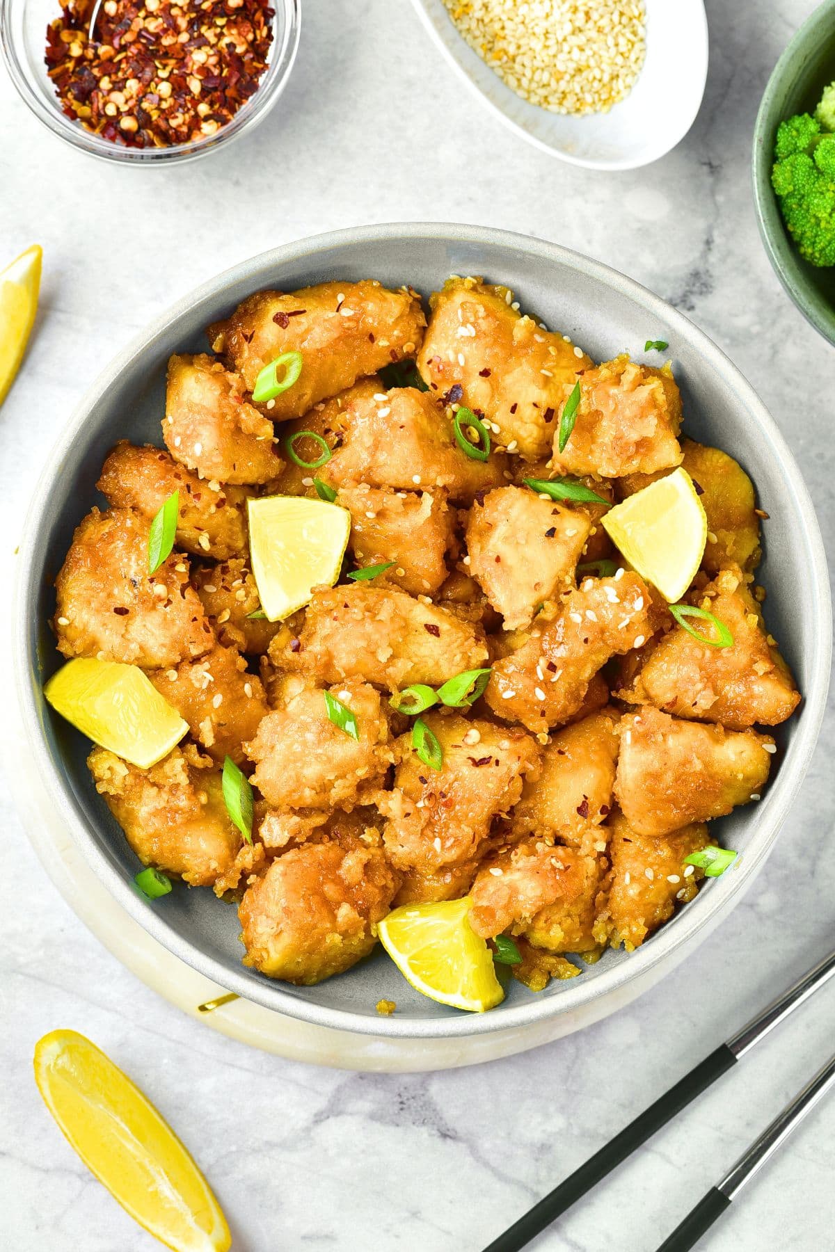 A bowl of Chinese lemon chicken on marble board.