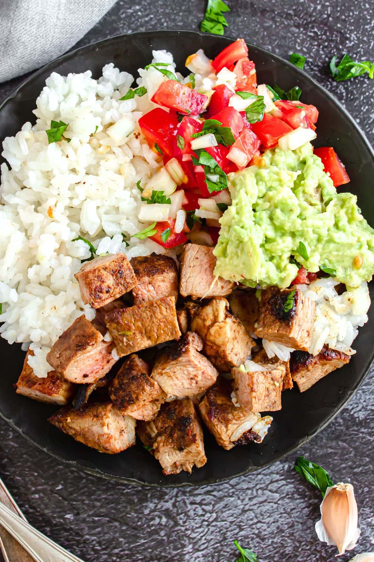 Easy Chipotle Steak Bowl (Gluten-Free, Dairy-Free) Top down view of bowl with steak cubes, guacamole, tomato salsa and rice.