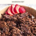 A bowl of coconut chocolate granola and sliced strawberries