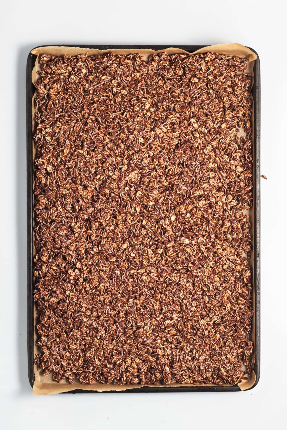 Homemade chocolate granola spread out on baking sheet