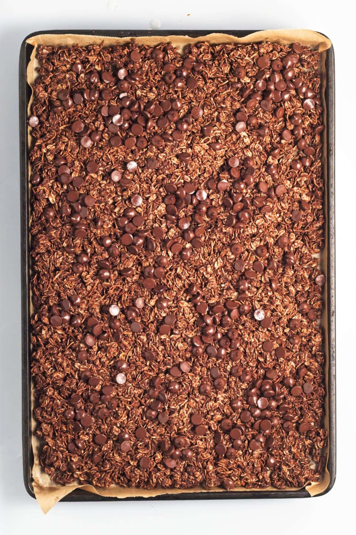 Granola topped with chocolate chips in baking sheet