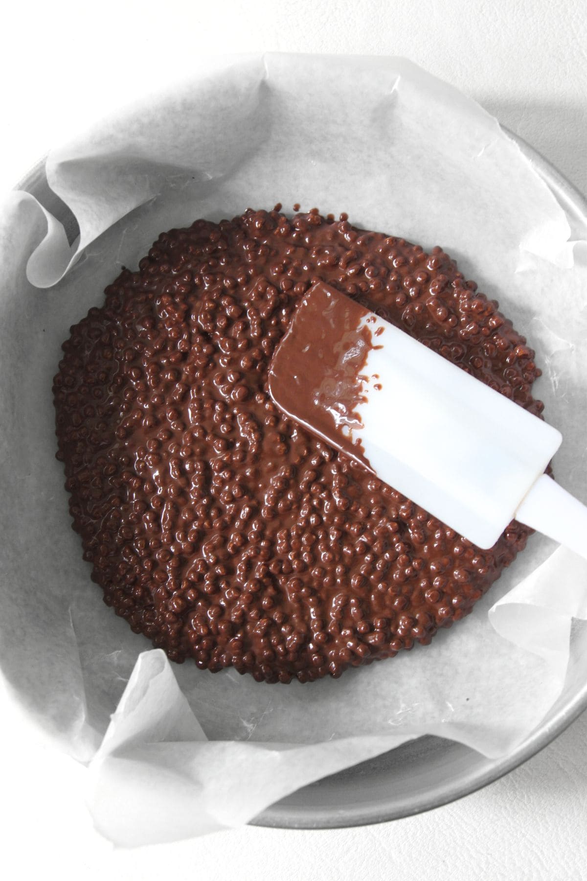 Using spatula to smooth out chocolate quinoa mixture in baking pan.
