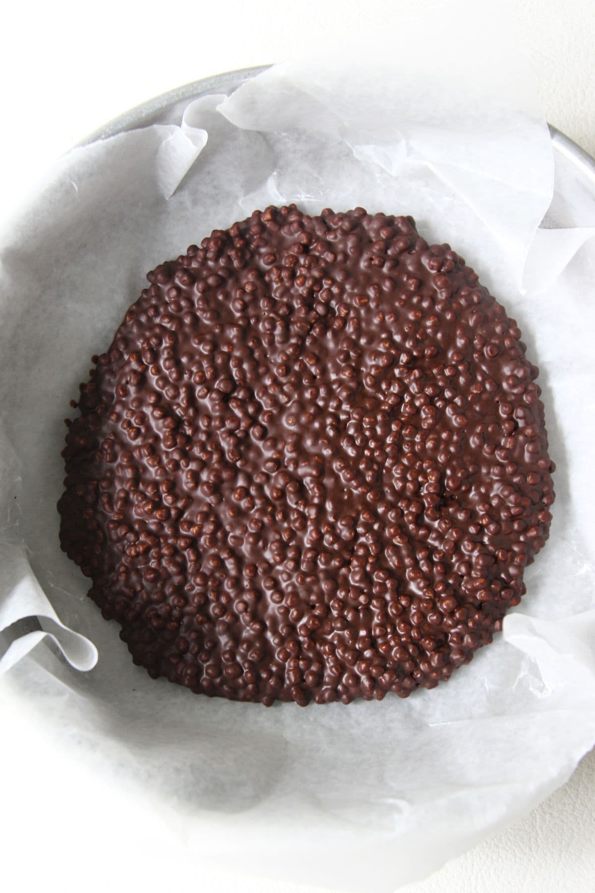 Chocolate-covered quinoa pops in parchment-lined pan.