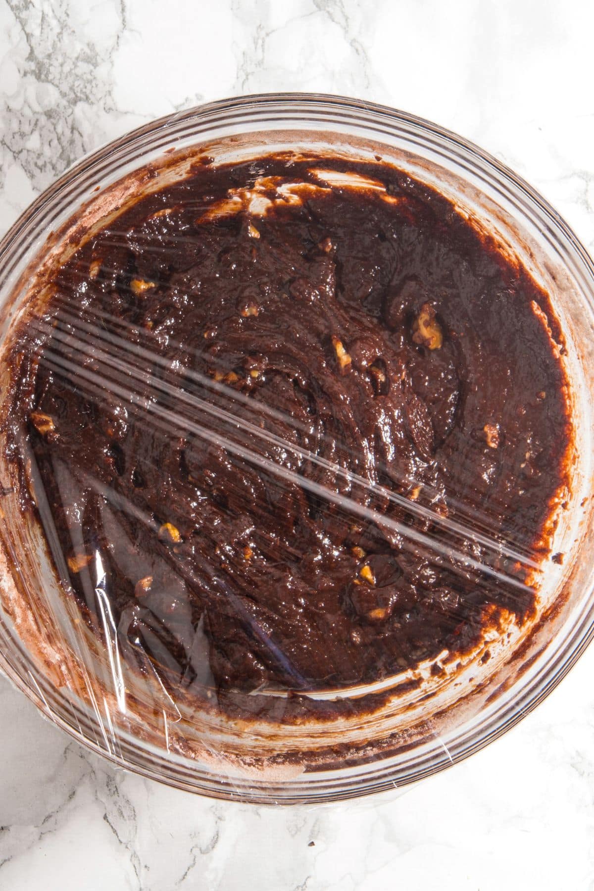A bowl of chocolate cookie dough wrapped in plastic wrap.