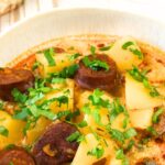 A bowl of soup with chorizo and potatoes