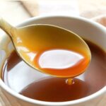 Holding up a spoonful of coconut caramel sauce from a bowl.