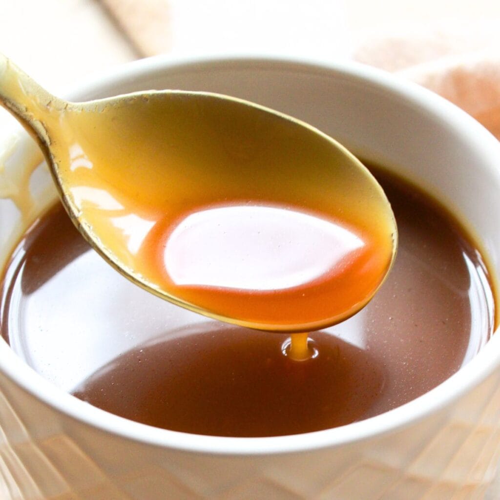 Holding up a spoonful of caramel from a bowl.
