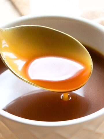 Holding up a spoonful of caramel from a bowl.