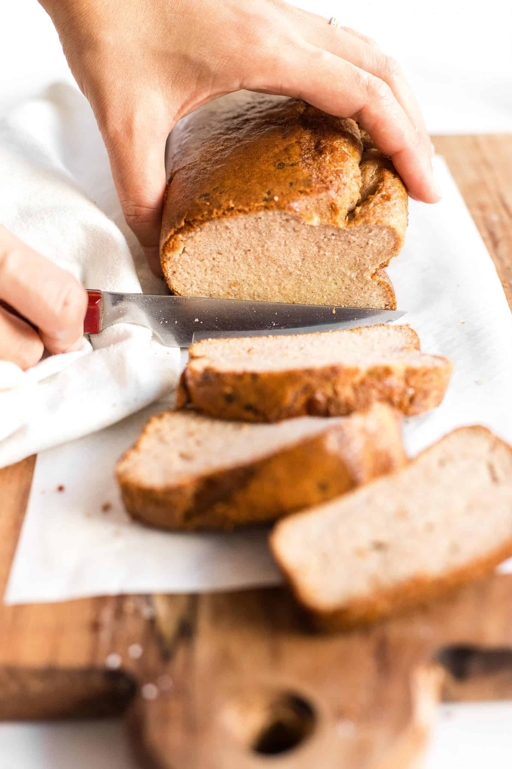 Slicing a loaf of coconut flour bread.