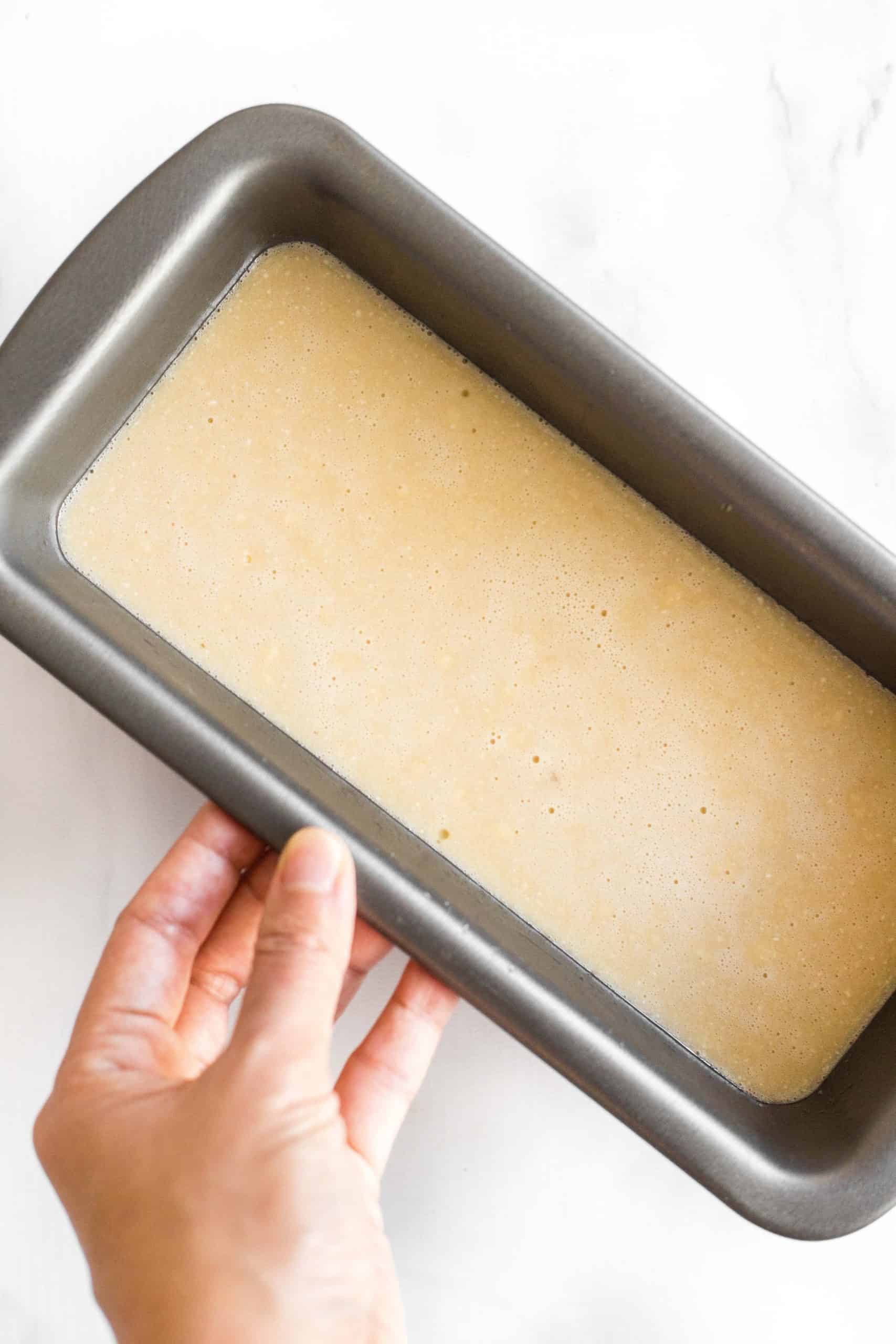 Holding a loaf pan filled with with coconut flour bread batter.