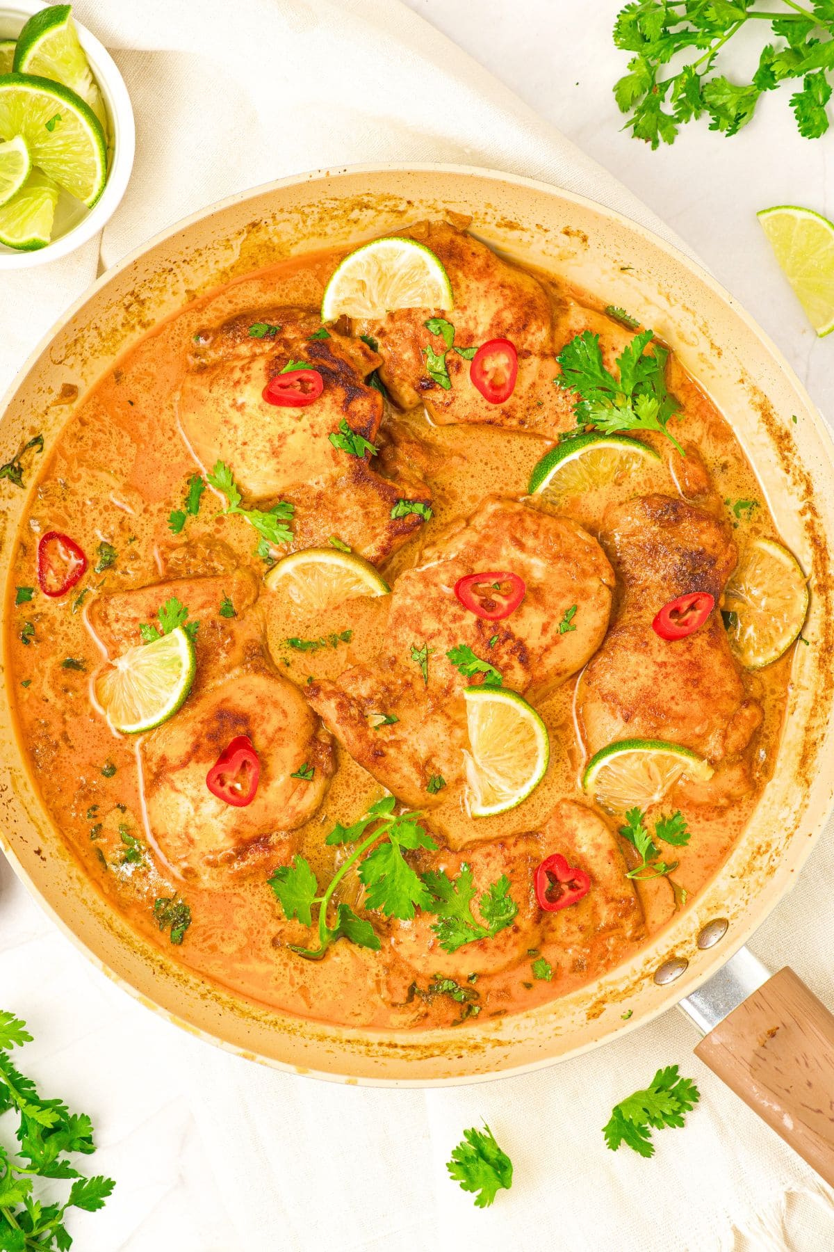 One-Pan Coconut Lime Chicken (Gluten-Free, Dairy-Free) Top down view of one-pan coconut lime chicken sprinkled with lime wedges and fresh cilantro.