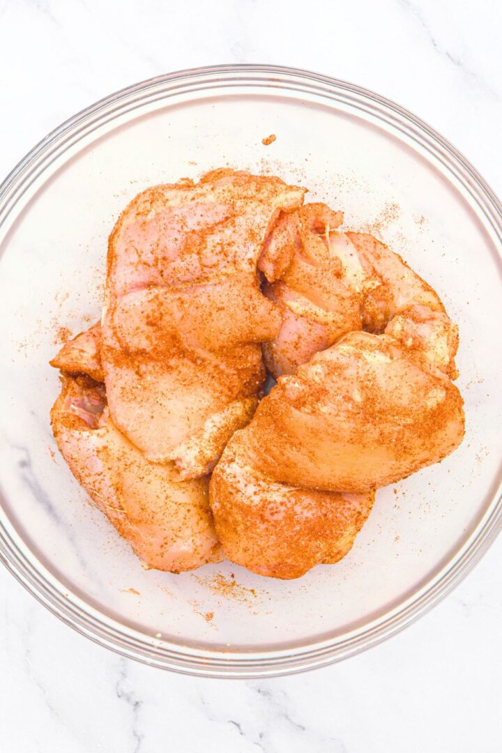 Seasoned chicken thighs in glass bowl