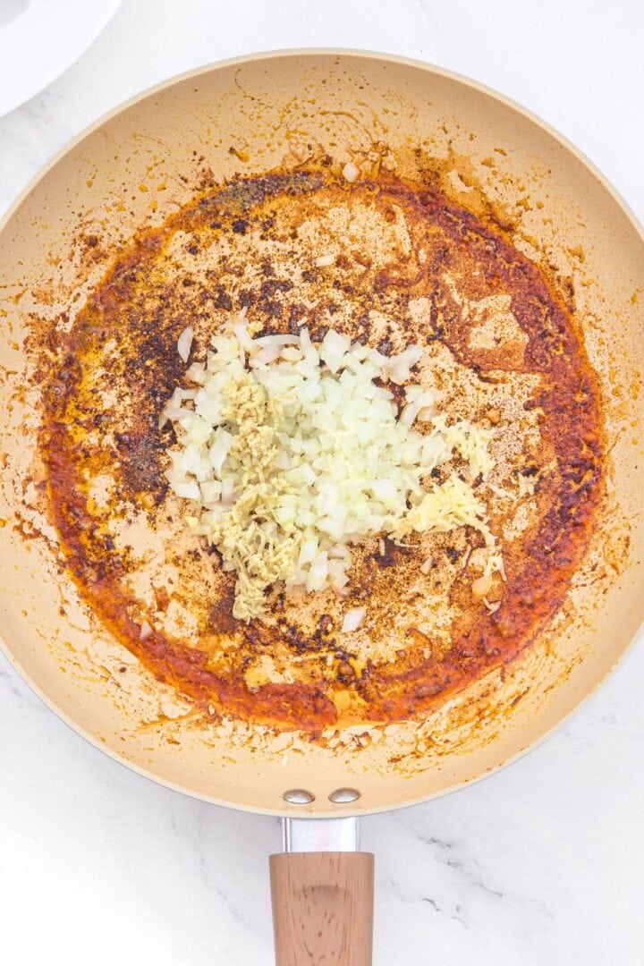 Cooking grated ginger, diced onions and minced garlic in skillet.