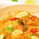 Up close view of a skillet with coconut and lime chicken thighs