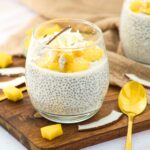A glass of coconut milk chia pudding topped with fresh mangoes