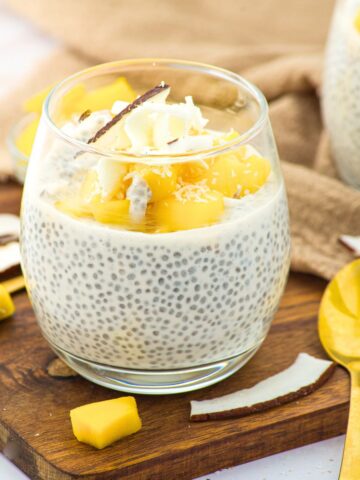 A glass of coconut milk chia pudding topped with fresh mangoes