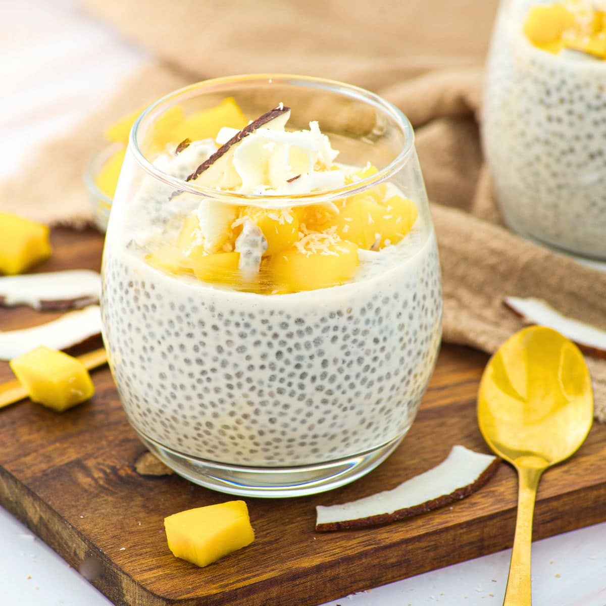 A glass of coconut milk chia pudding topped with fresh mangoes