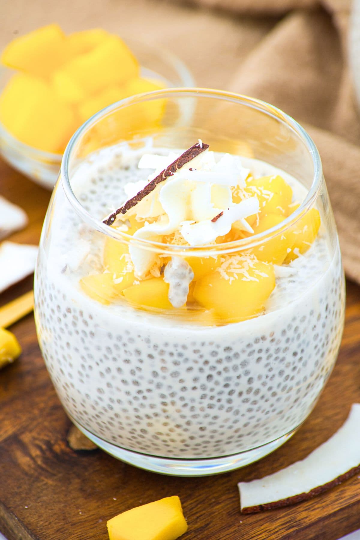 Up close view of a glass of coconut milk chia pudding topped with fresh mango.