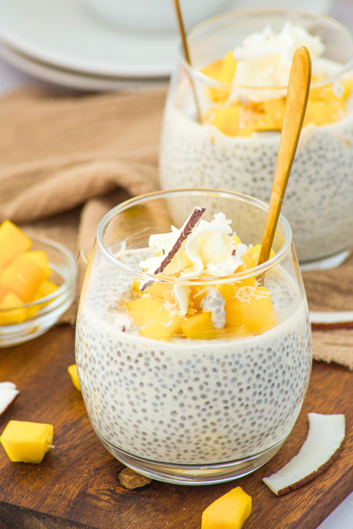 Glasses of chia and coconut milk pudding on wooden board.