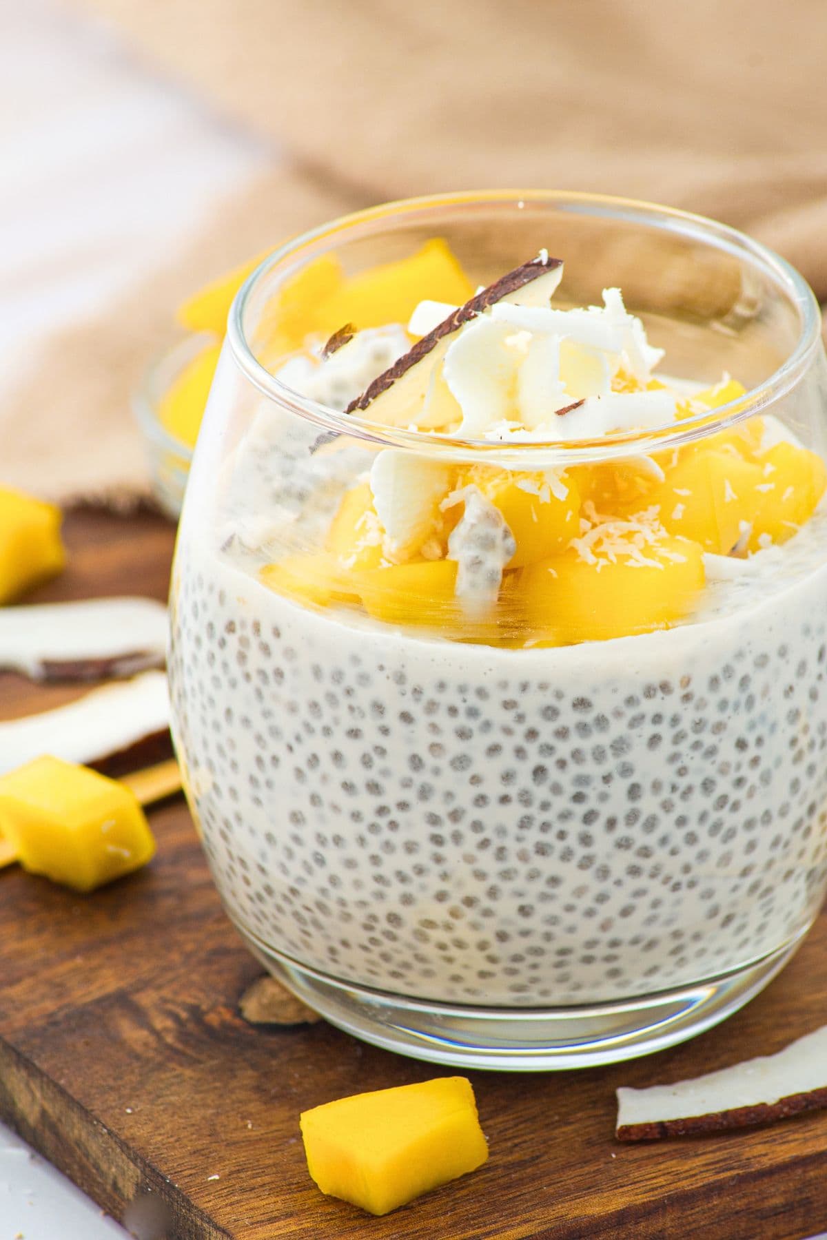 Up close view of a class of coconut milk chia pudding topped with cubed mango