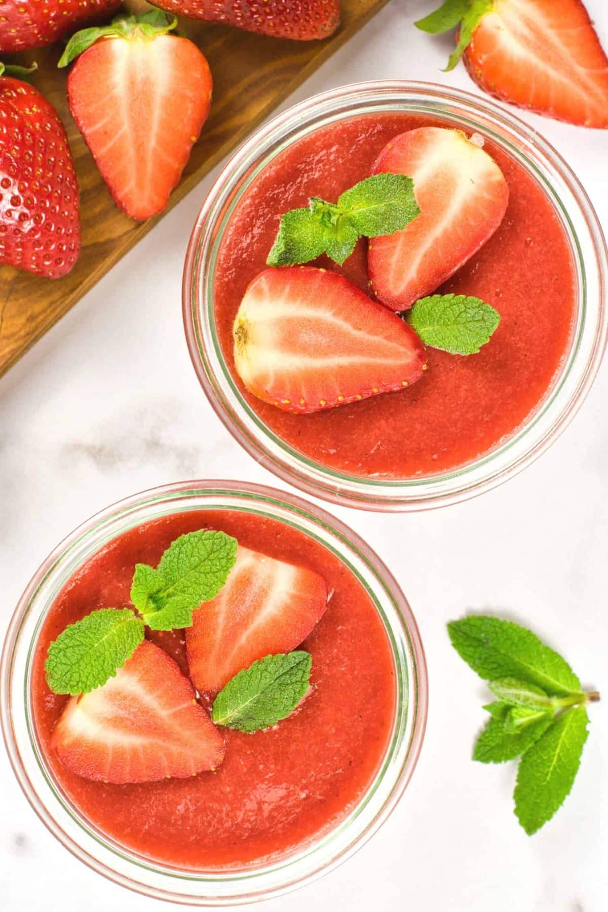 Top down view of strawberry sauce in bowls topped with sliced strawberries.