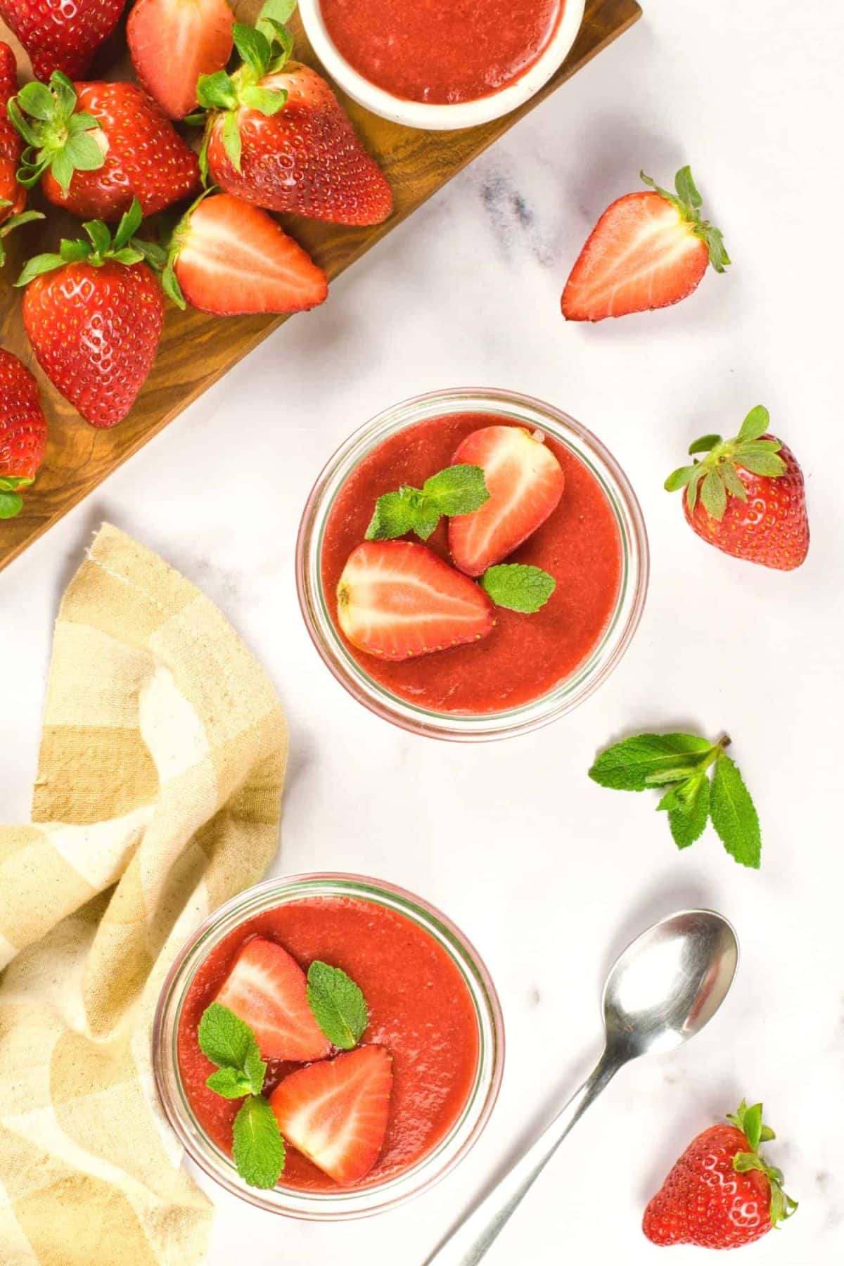 Top down view of jars of strawberry panna cotta on marble board.