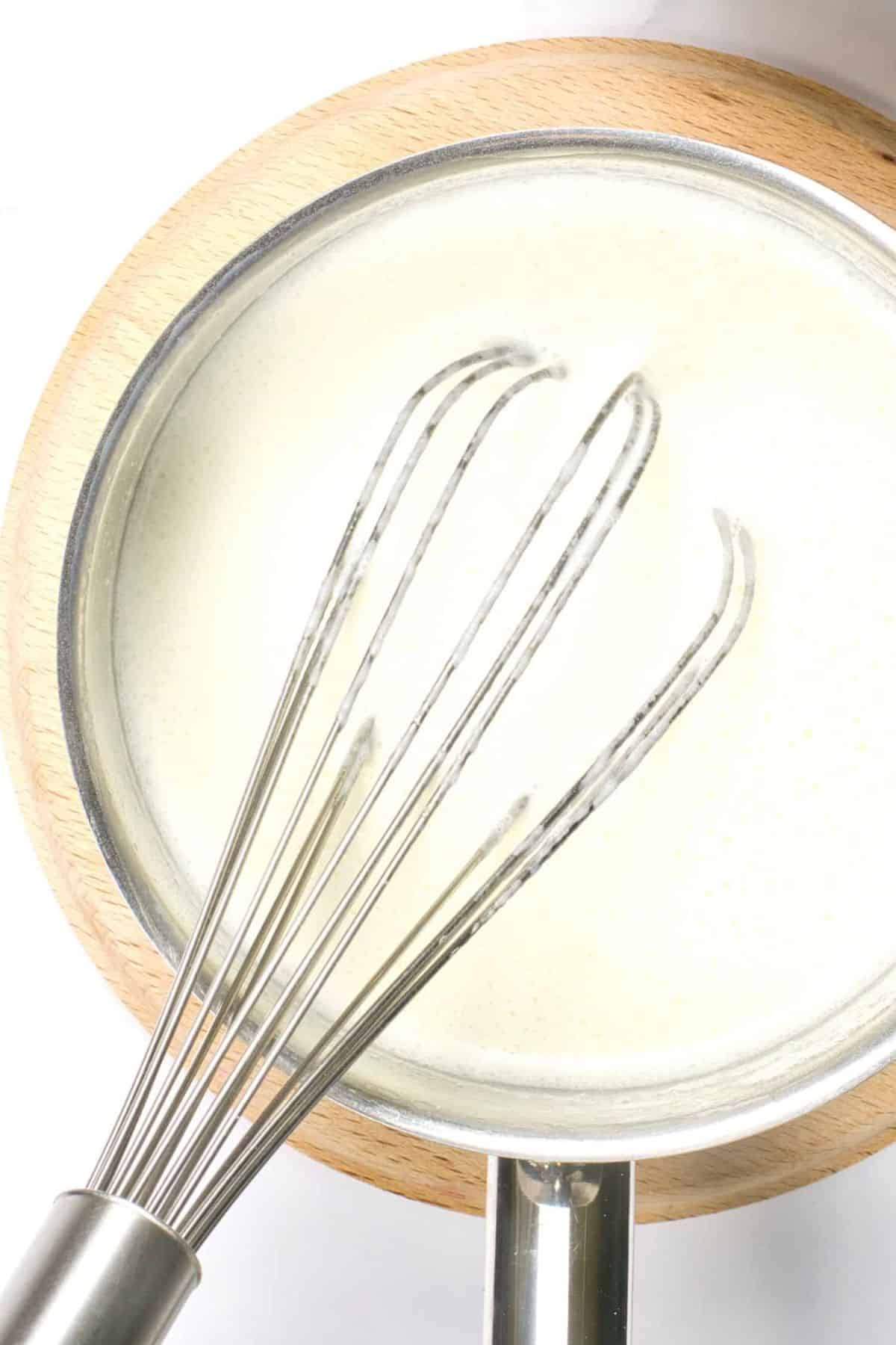 Whisking coconut milk mixture in saucepan.