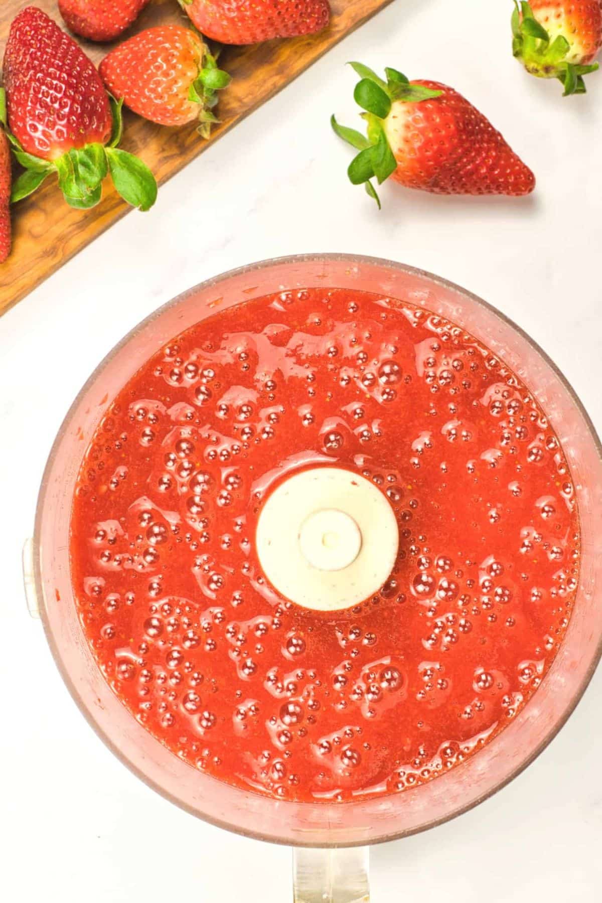 Top down view of strawberry liquid mixture in food processor.