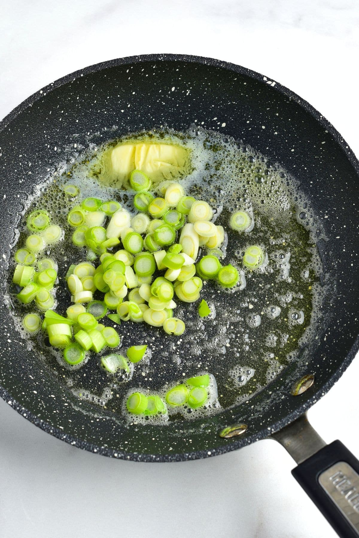 Sautéing chopped green onions in melted butter