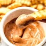Dipping a french fry into homemade raising cane's sauce