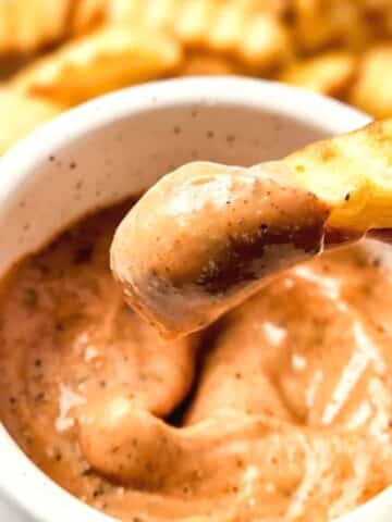 Dipping a french fry into homemade raising cane's sauce