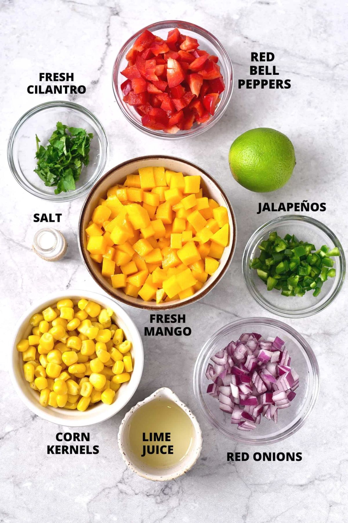 Ingredients for making corn mango salsa laid out on marble board.