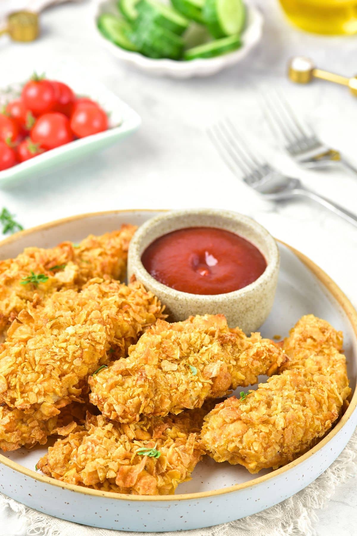 A plate of cornflake breaded chicken strips and ketchup.