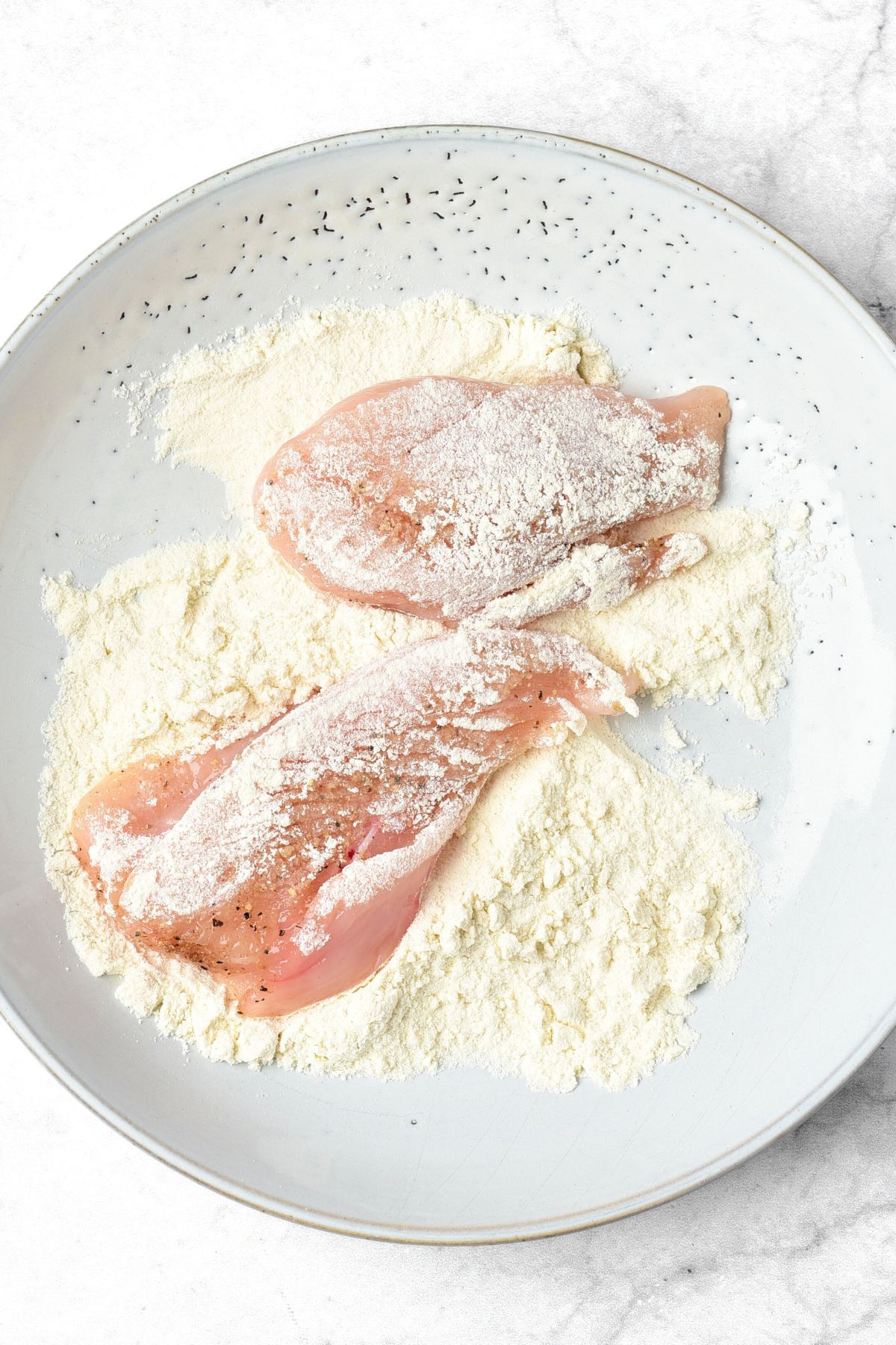 Coating raw chicken pieces in flour