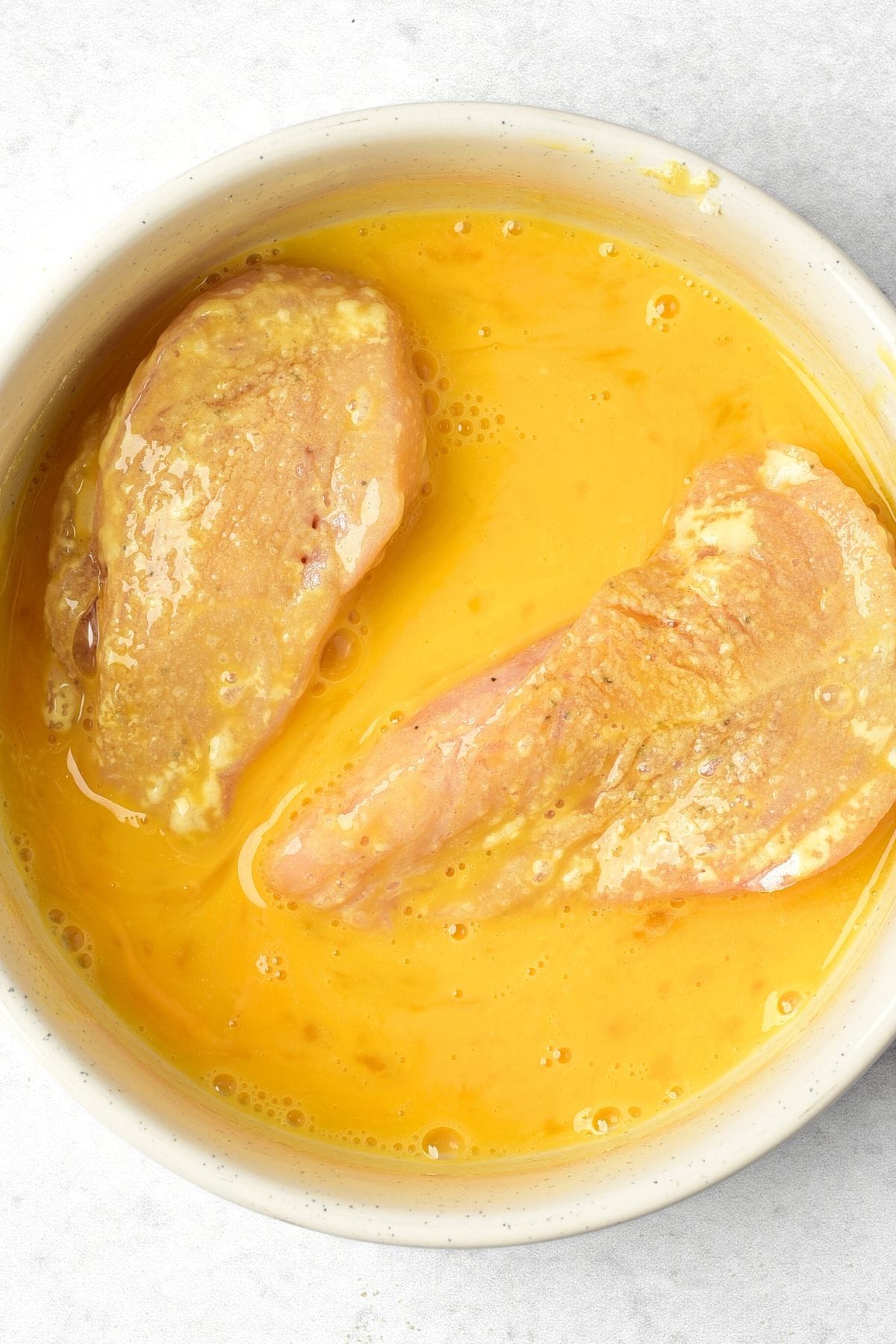 Dipping chicken in beaten egg