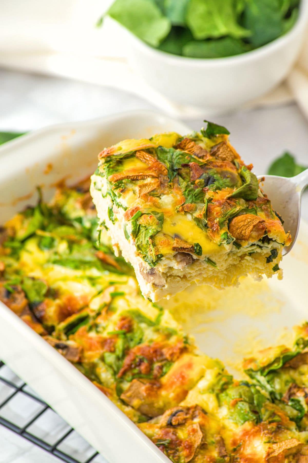 Holding up a slice of cottage cheese and egg bake from casserole dish