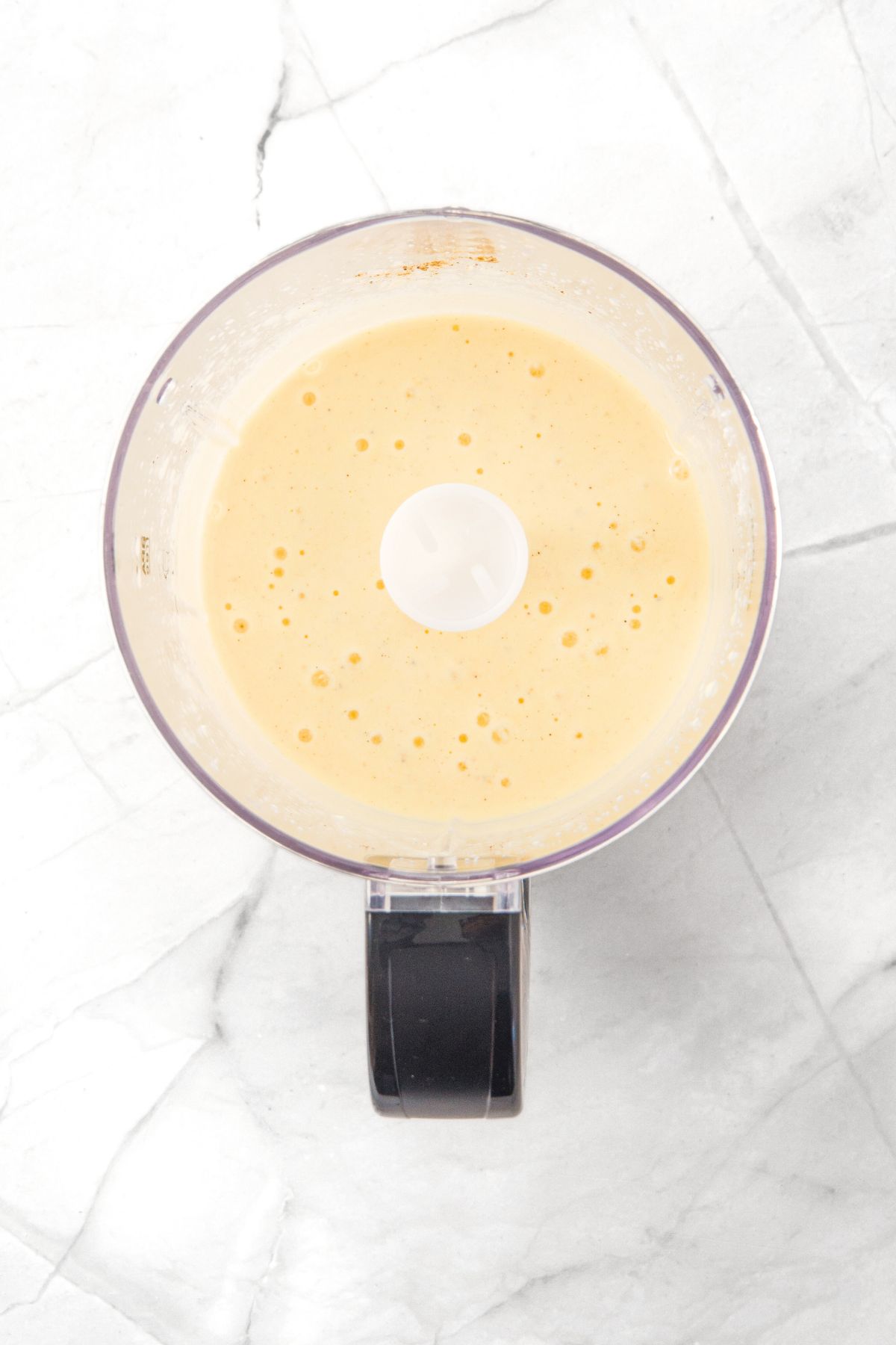 Pale yellow liquid mixture in food processor.