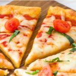 Up close view of pizza slices on wooden board