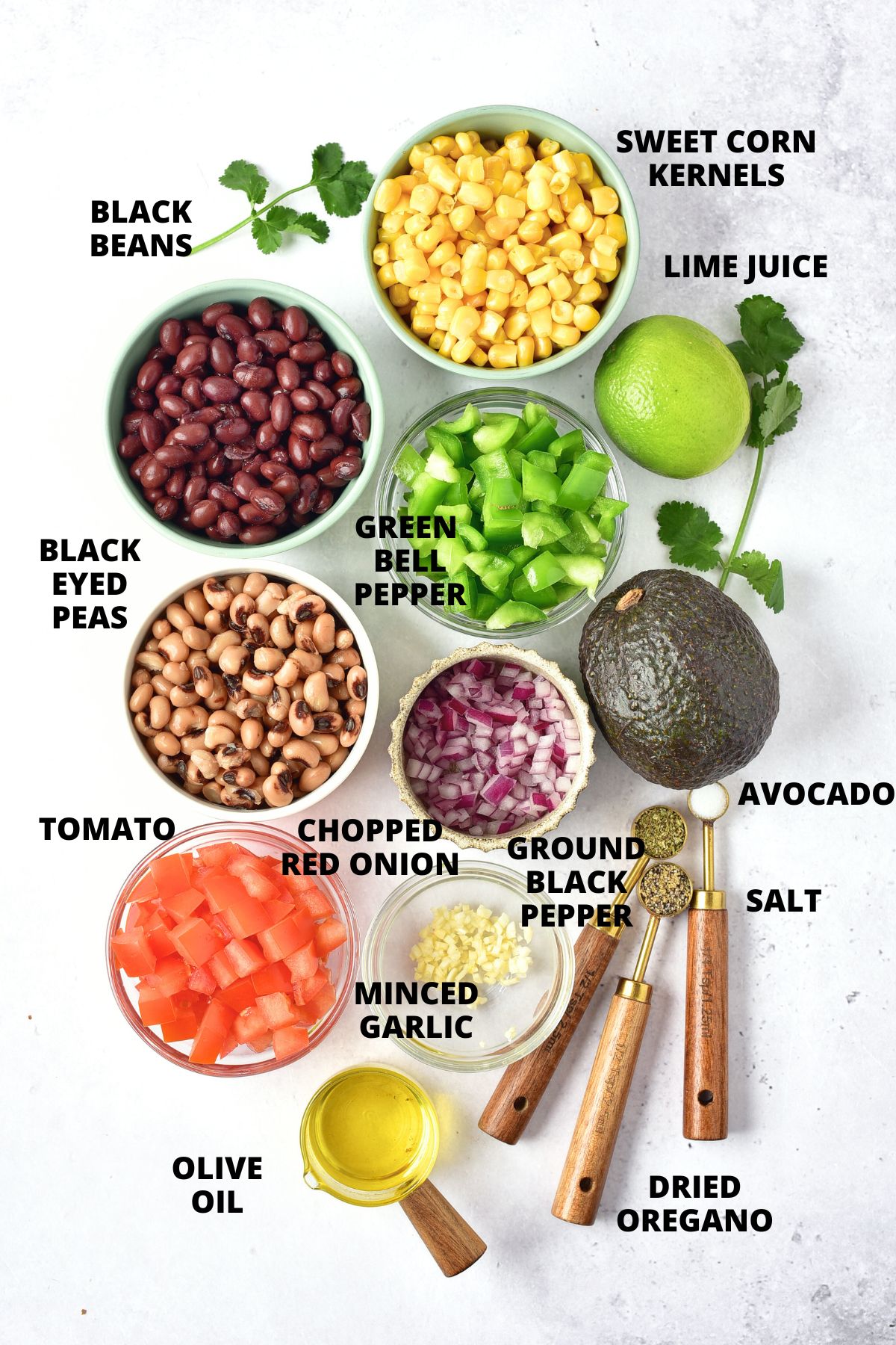 Ingredients for cowboy caviar recipe laid out on white board.