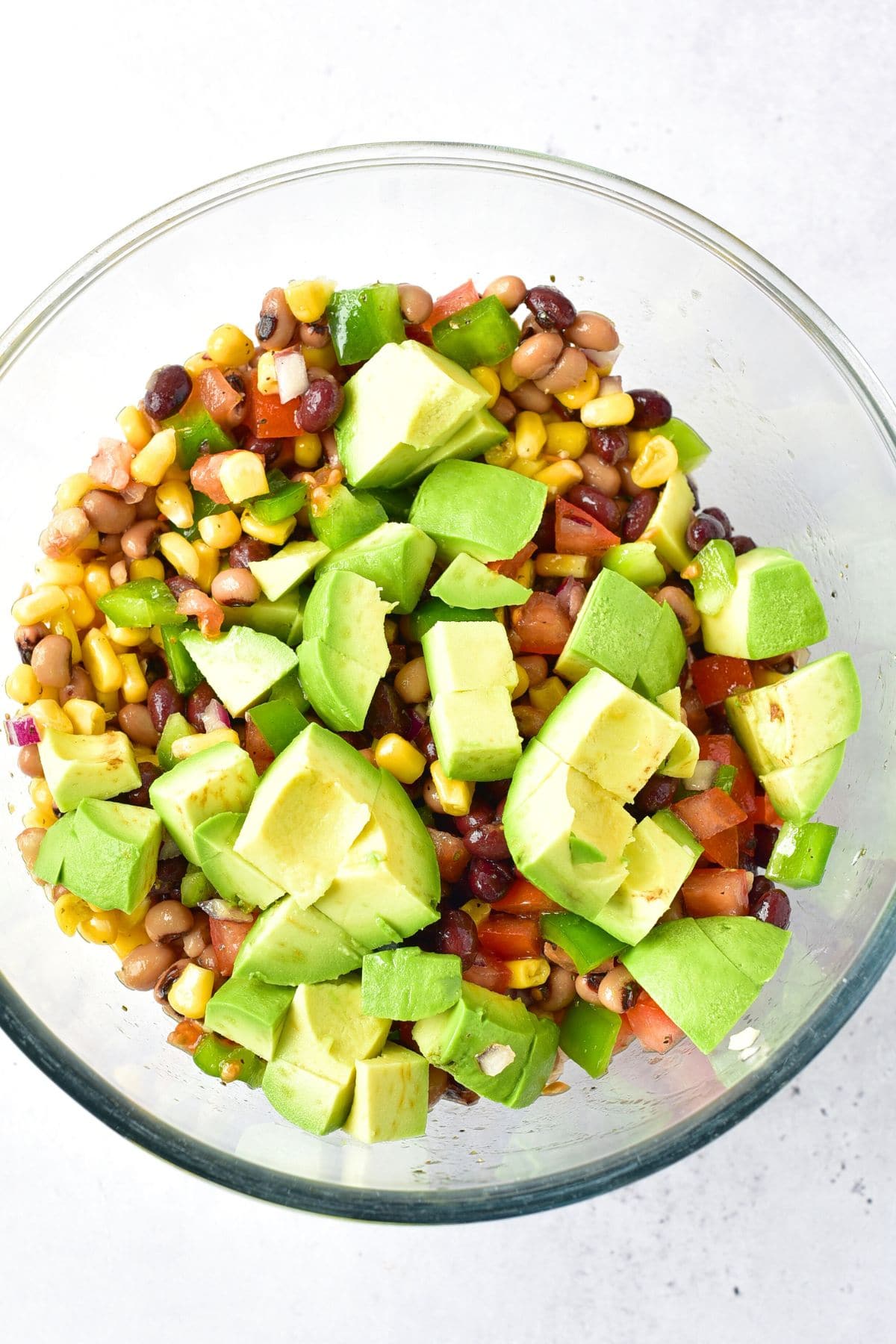 Diced avocado on top of a bowl of bean salad.