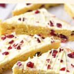Cranberry bliss bars on wooden board.