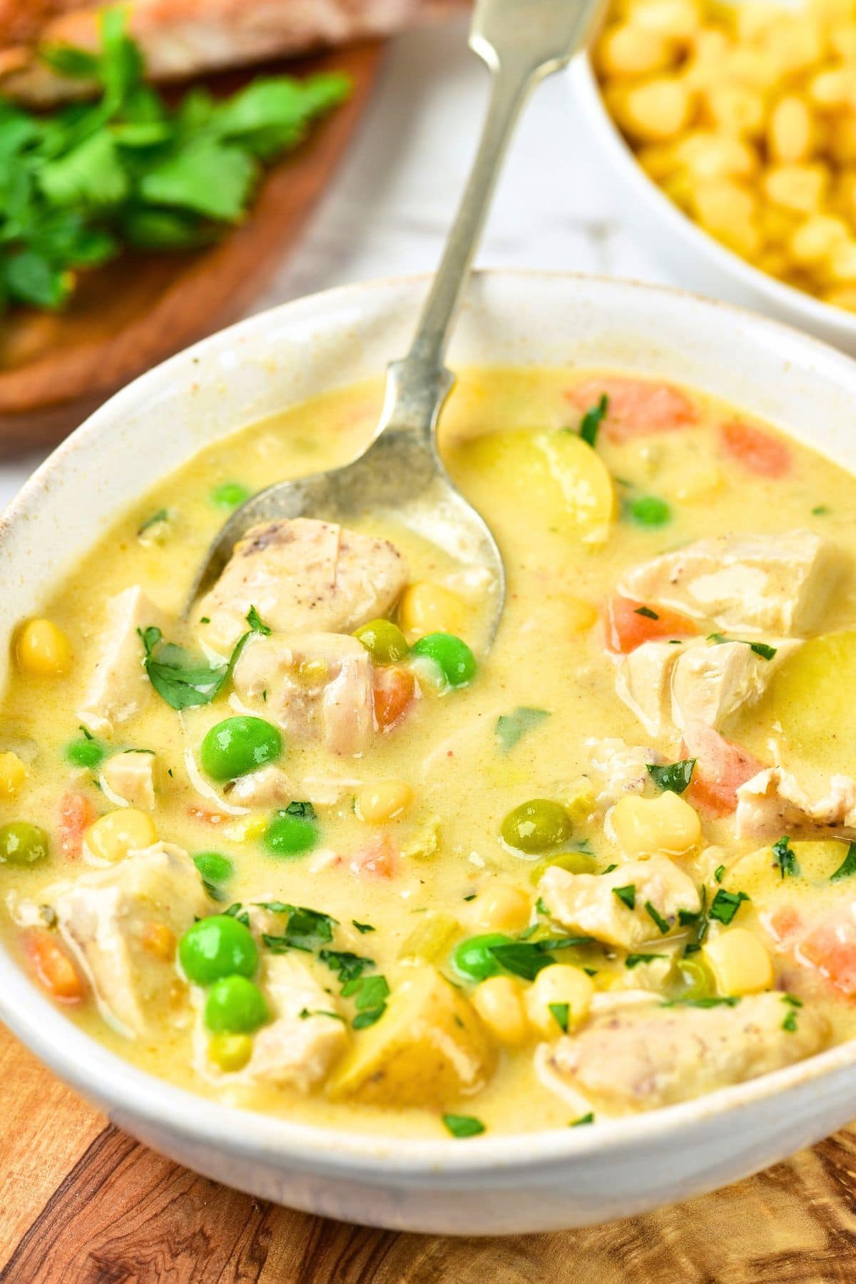 A spoon in a bowl of creamy chicken potato soup.