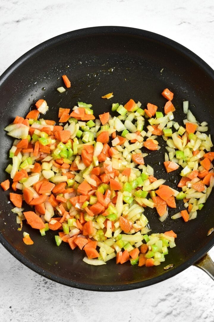 Sautéing diced carrots, onions and celery in skillet